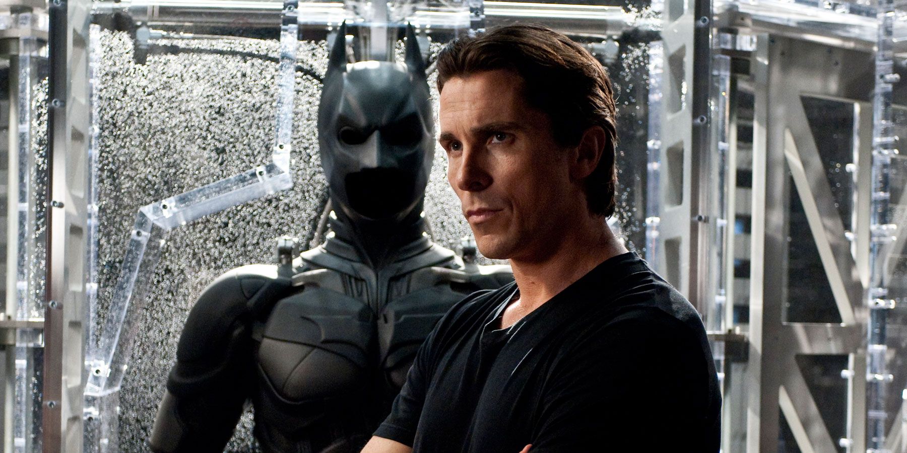 Christian Bale as Bruce Wayne in front of his suit