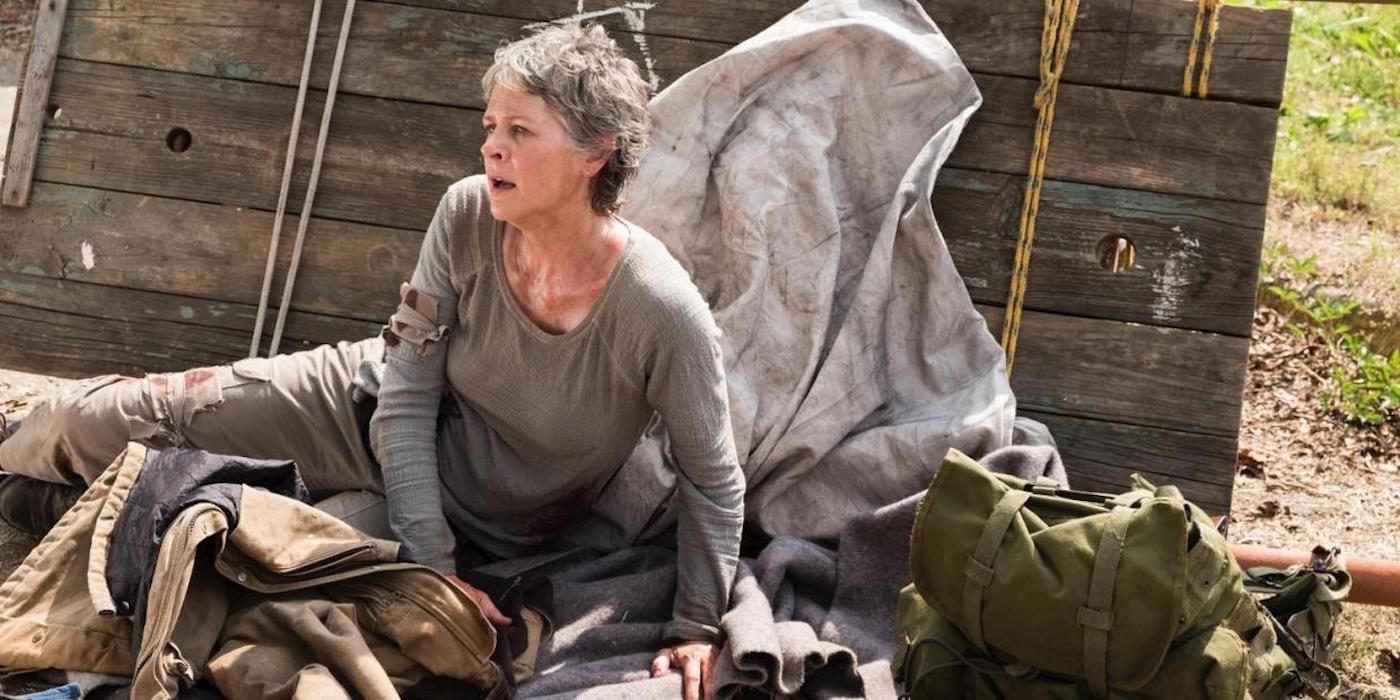 Carol sleeping on the ground with a backpack in a scene from The Walking Dead.