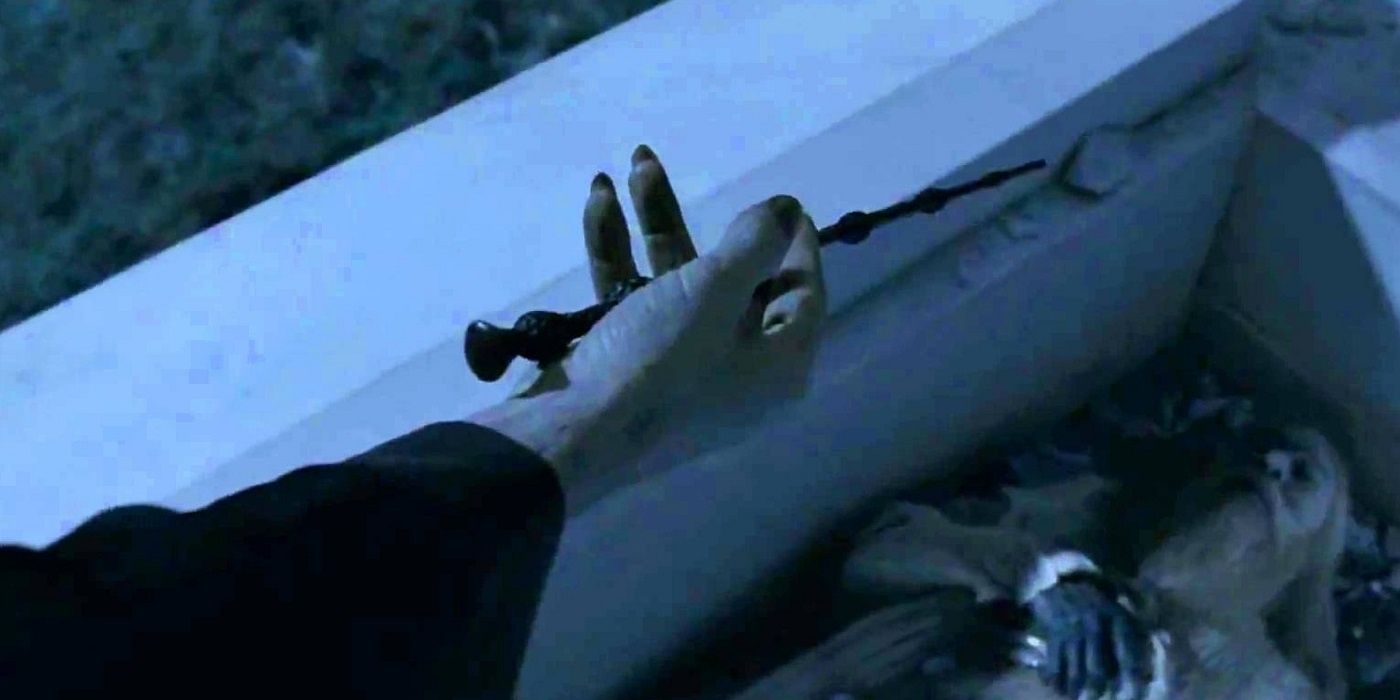 Voldemort taking the Elder Wand from Dumbledore's tomb in Harry Potter.