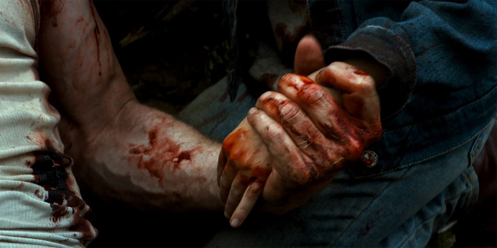 Laura holds Logan's bloodied hand in Logan