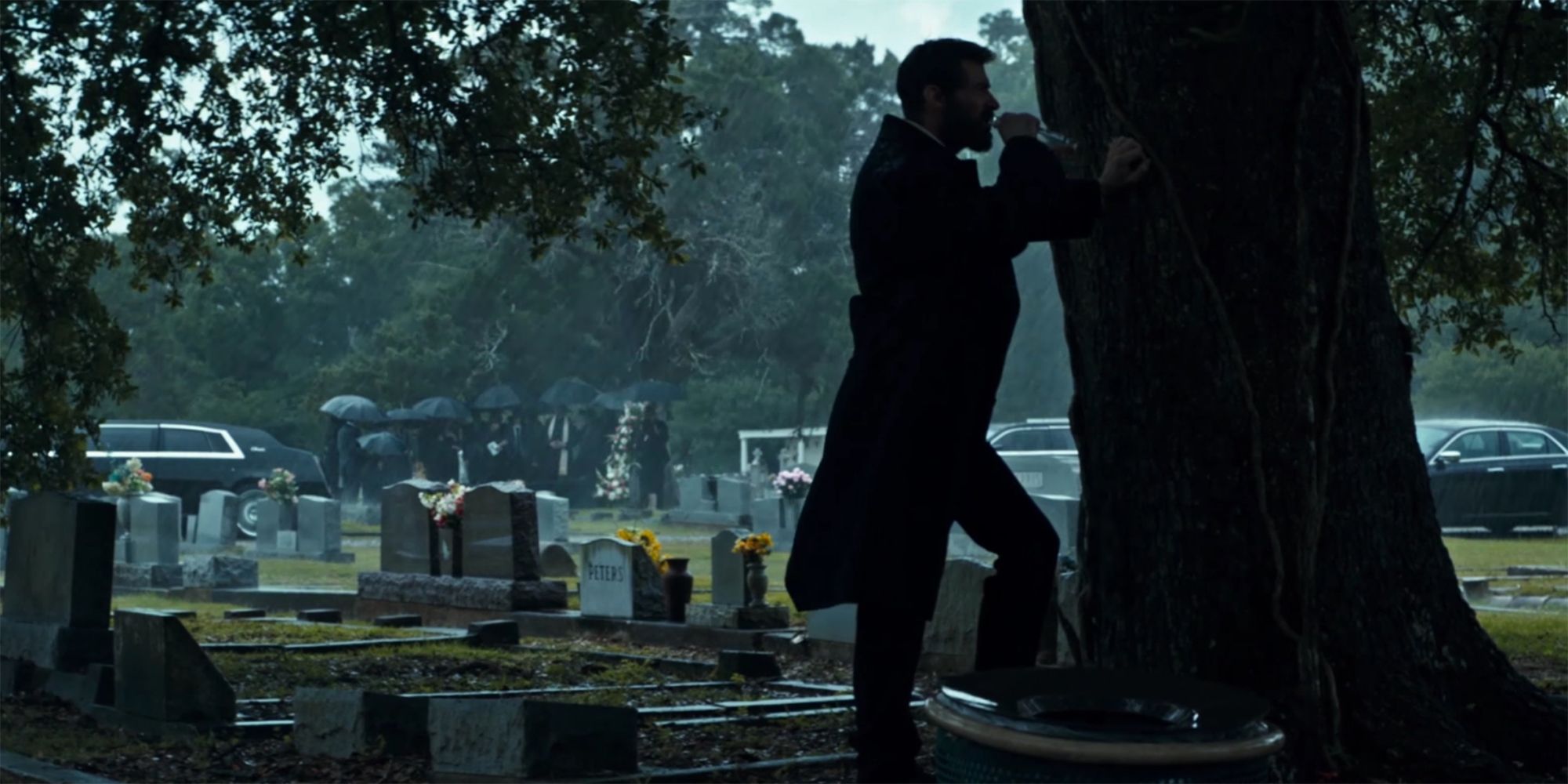 Logan leaning against a tree in a graveyard