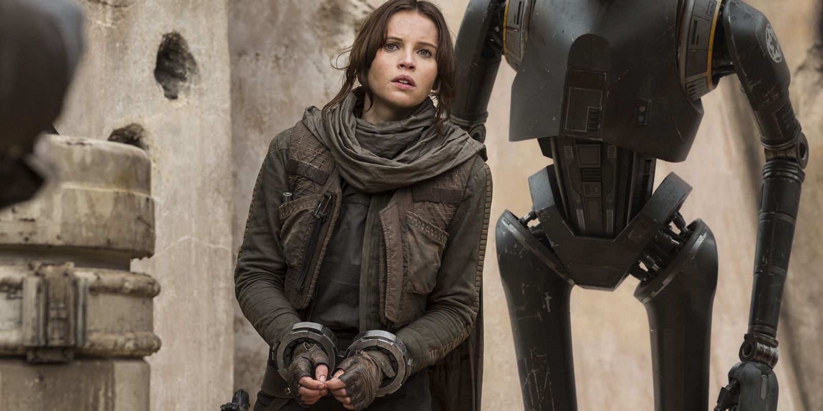 Jyn standing with her hands cuffed and K-2SO behind her in Rogue One: A Star Wars Story