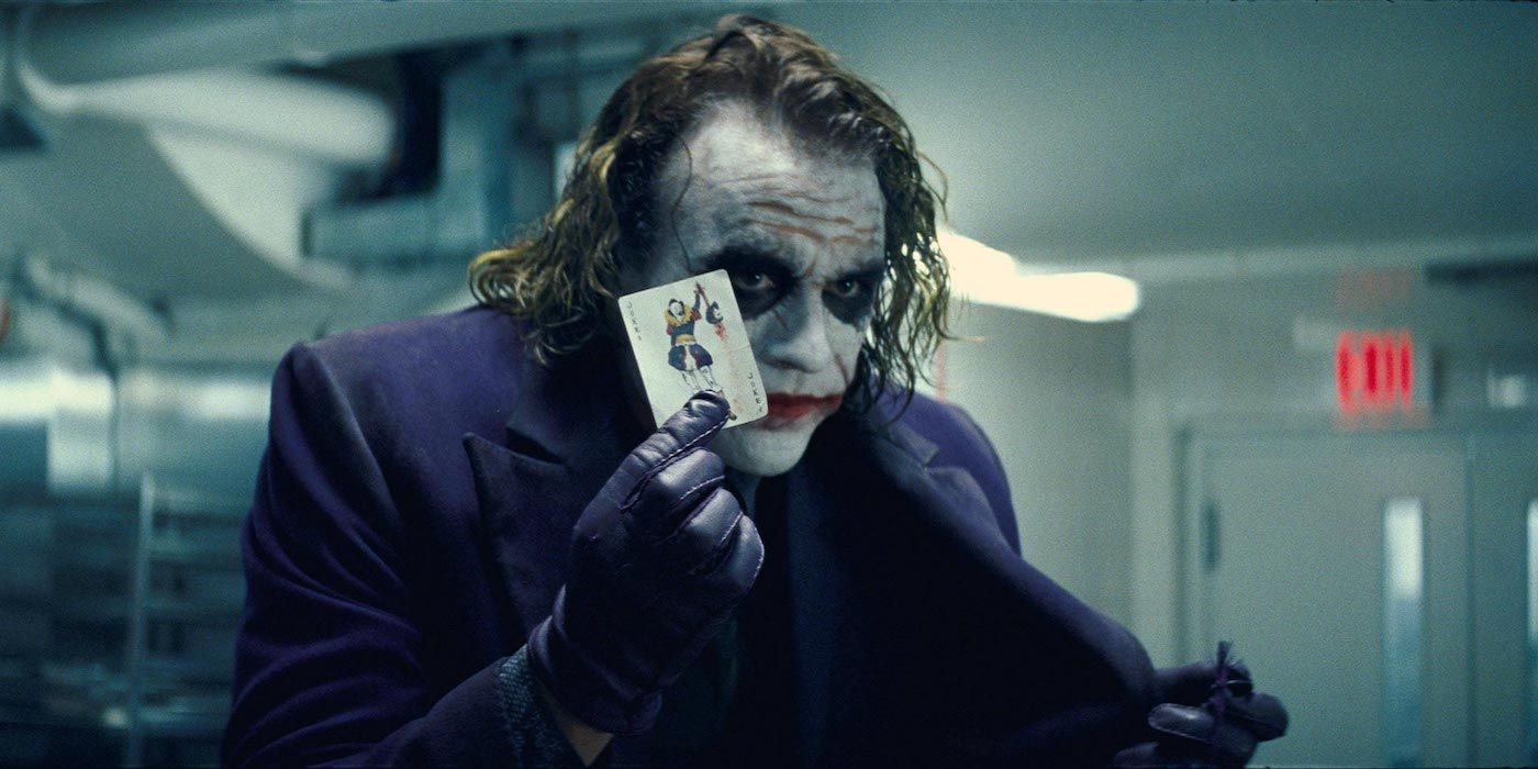 The Dark Knight's Joker holds up a joker card