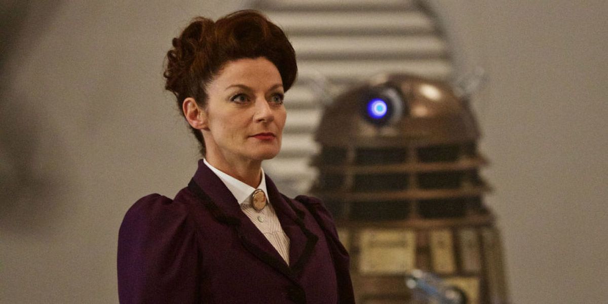 Michelle Gomez as Missy stands confidently in front of a Dalek in Doctor Who