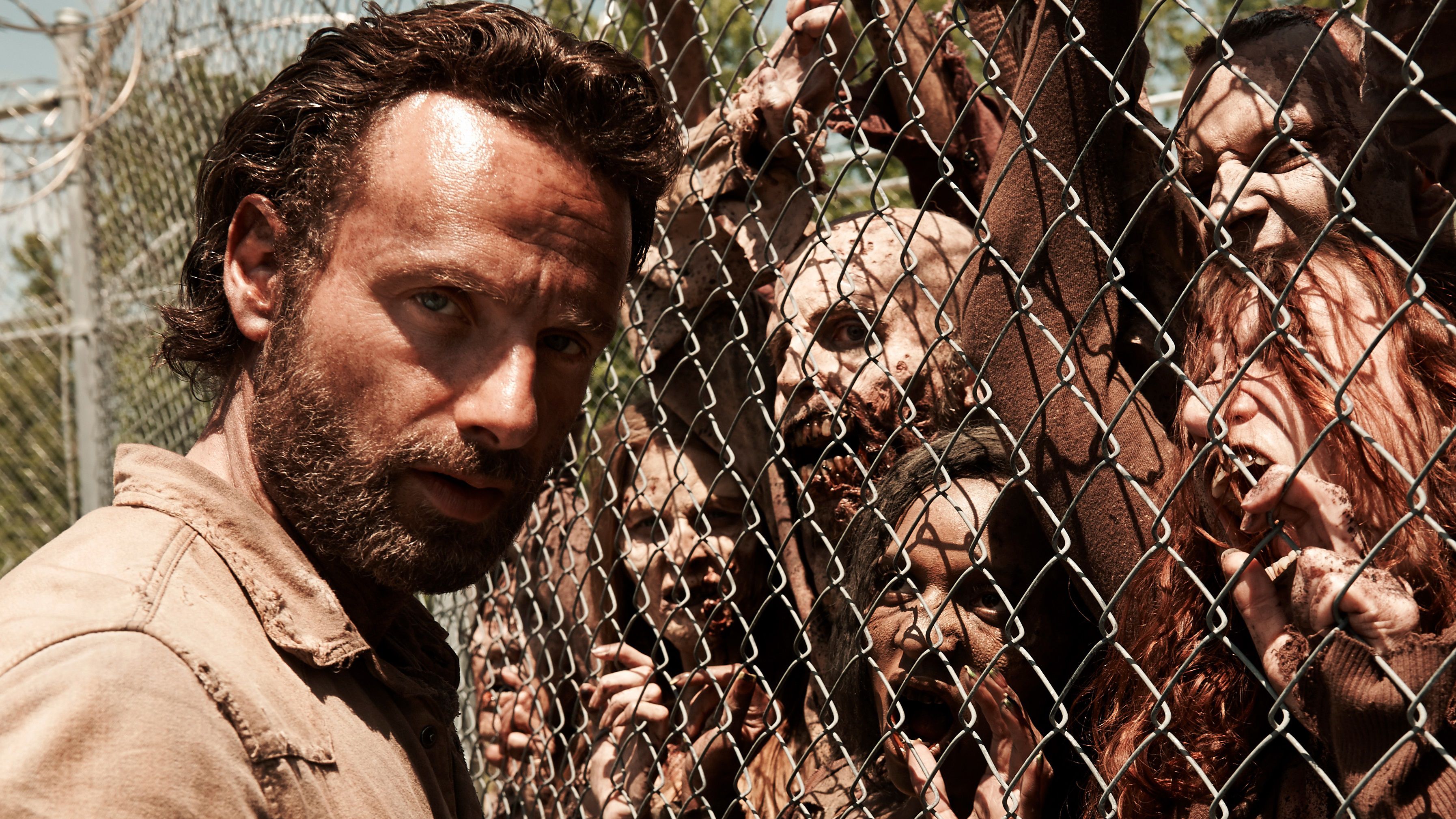 Rick next to a horde of zombies behind a fence The Walking Dead