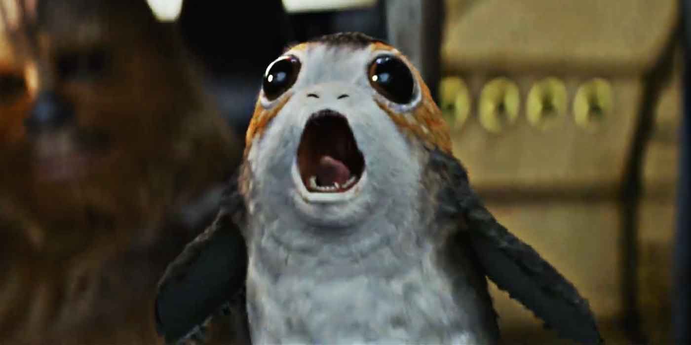 A porg screams on board the Millenium Falcon as Chewbacca looks on in Star Wars: The Last Jedi.