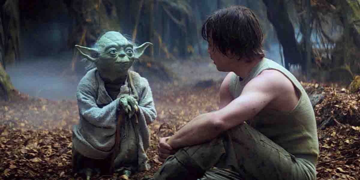 Luke se sienta junto a Yoda en un suelo cubierto de hojas durante The Empire Strikes Back.