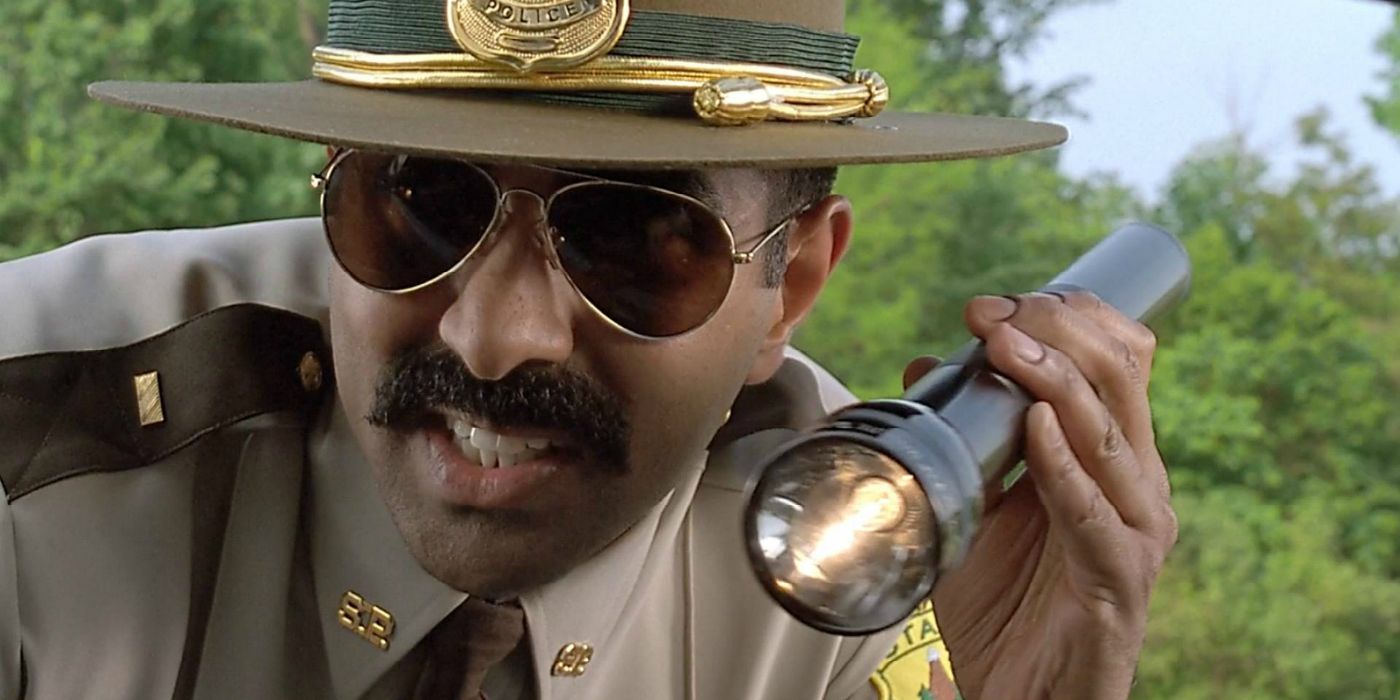 Jay Chandrasekhar shines a flashlight in a vehicle during his role during Super Troopers