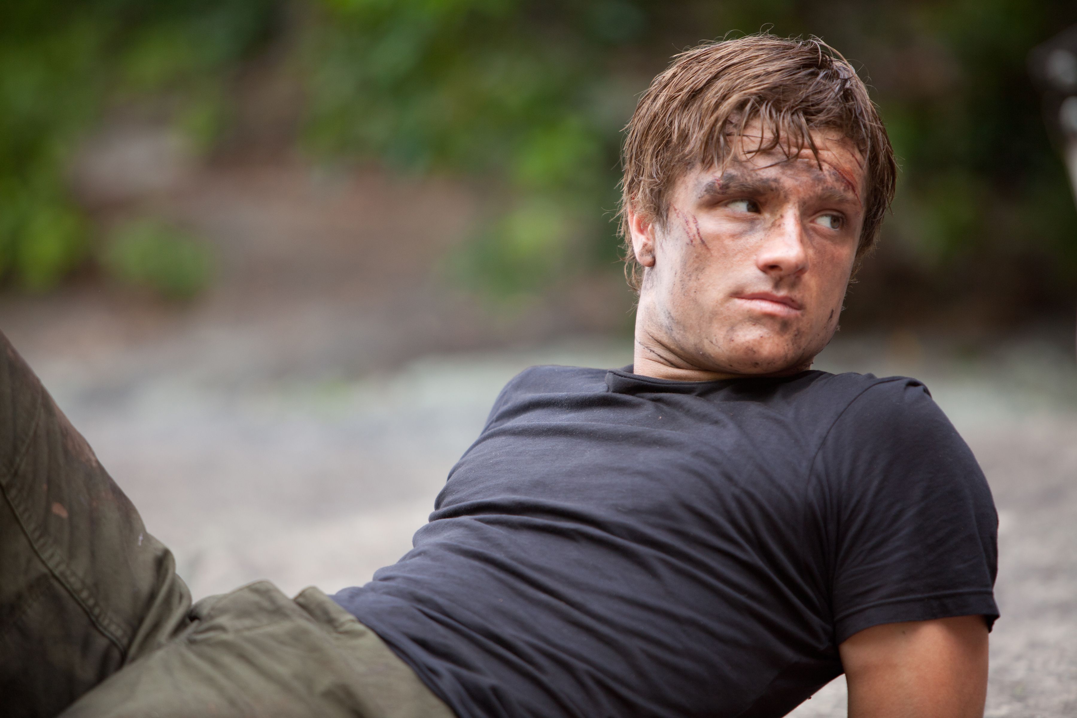 Josh Hutcherson's Peeta Mellark leaning back on a rock in The Hunger Games.