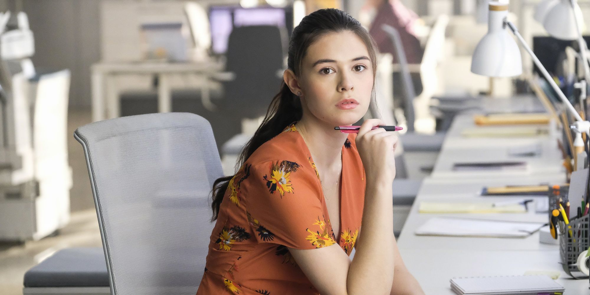 nia nal in supergirl sitting on her desk