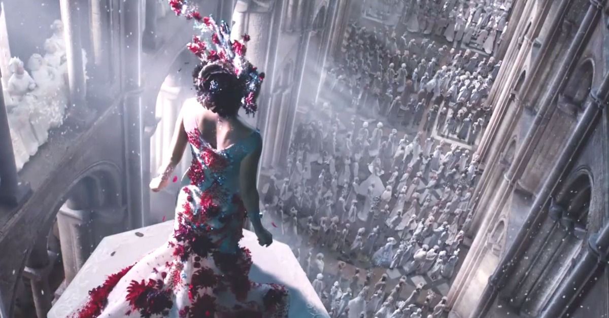 Jupiter Jones wears a red and white dress while over a crowd in Jupiter Ascending