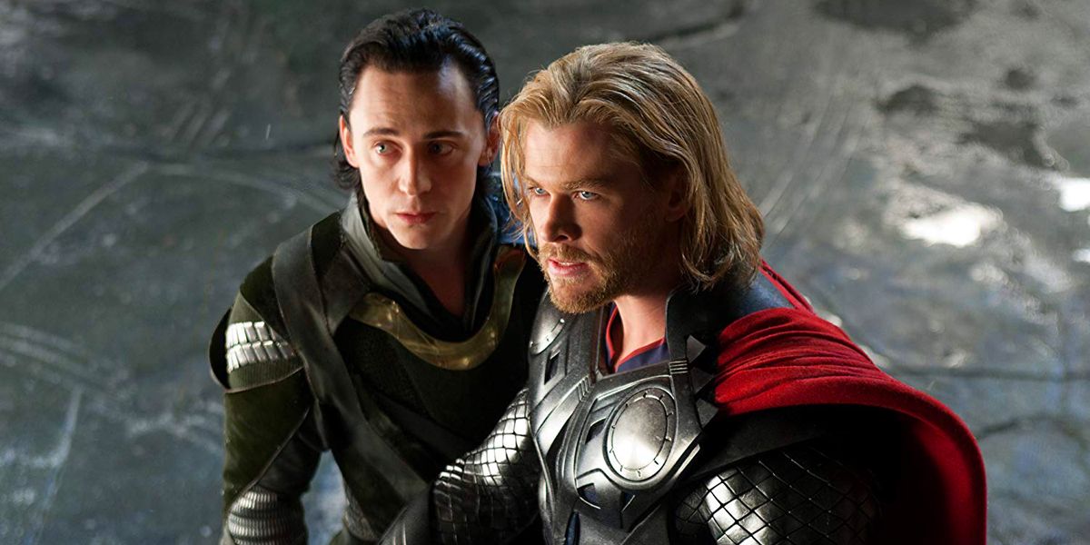Loki standing close to Thor while both look stressed and to the left
