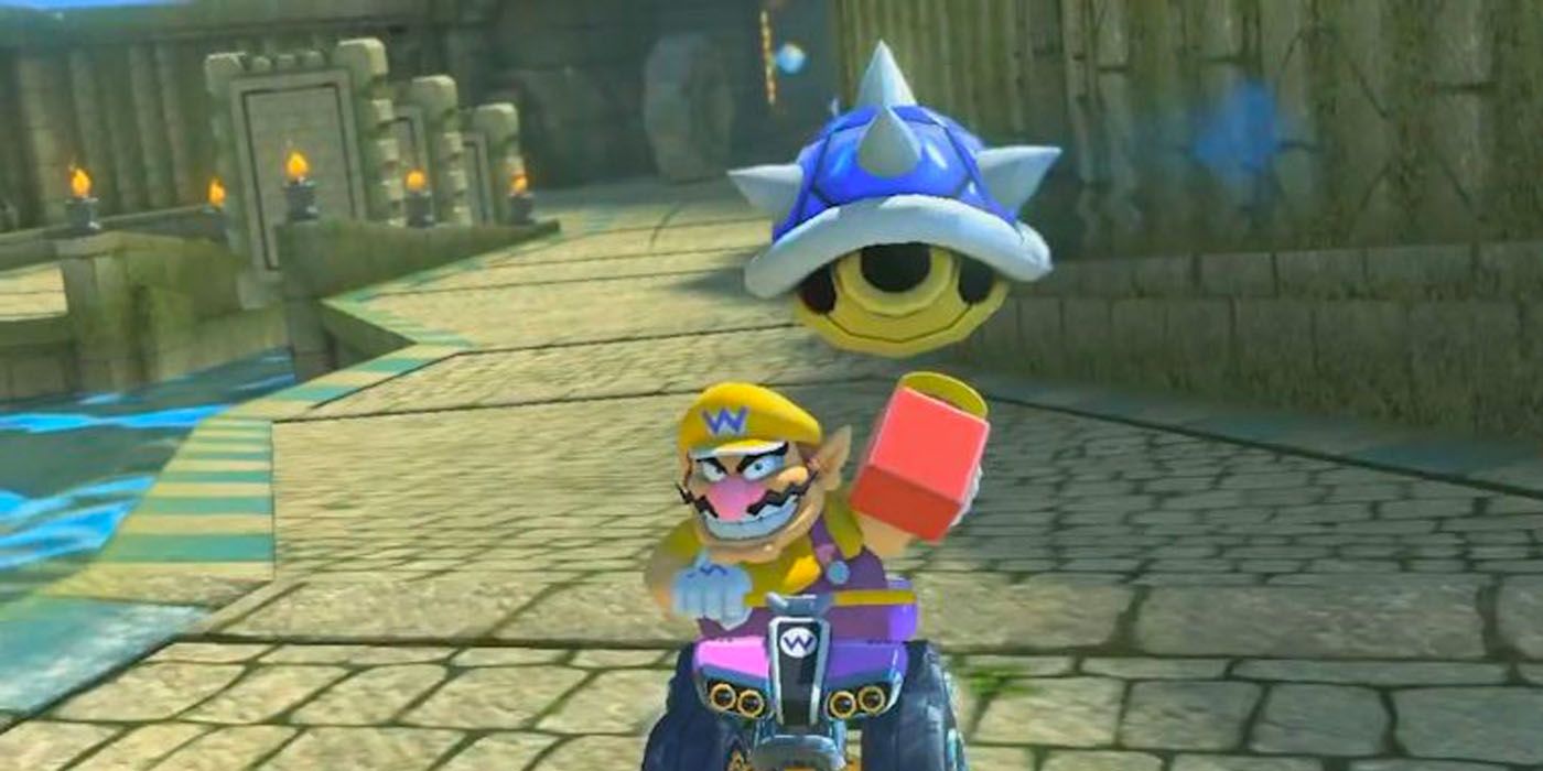 A flying Blue Shell in front of Wario driving a kart from Mario Kart 8.