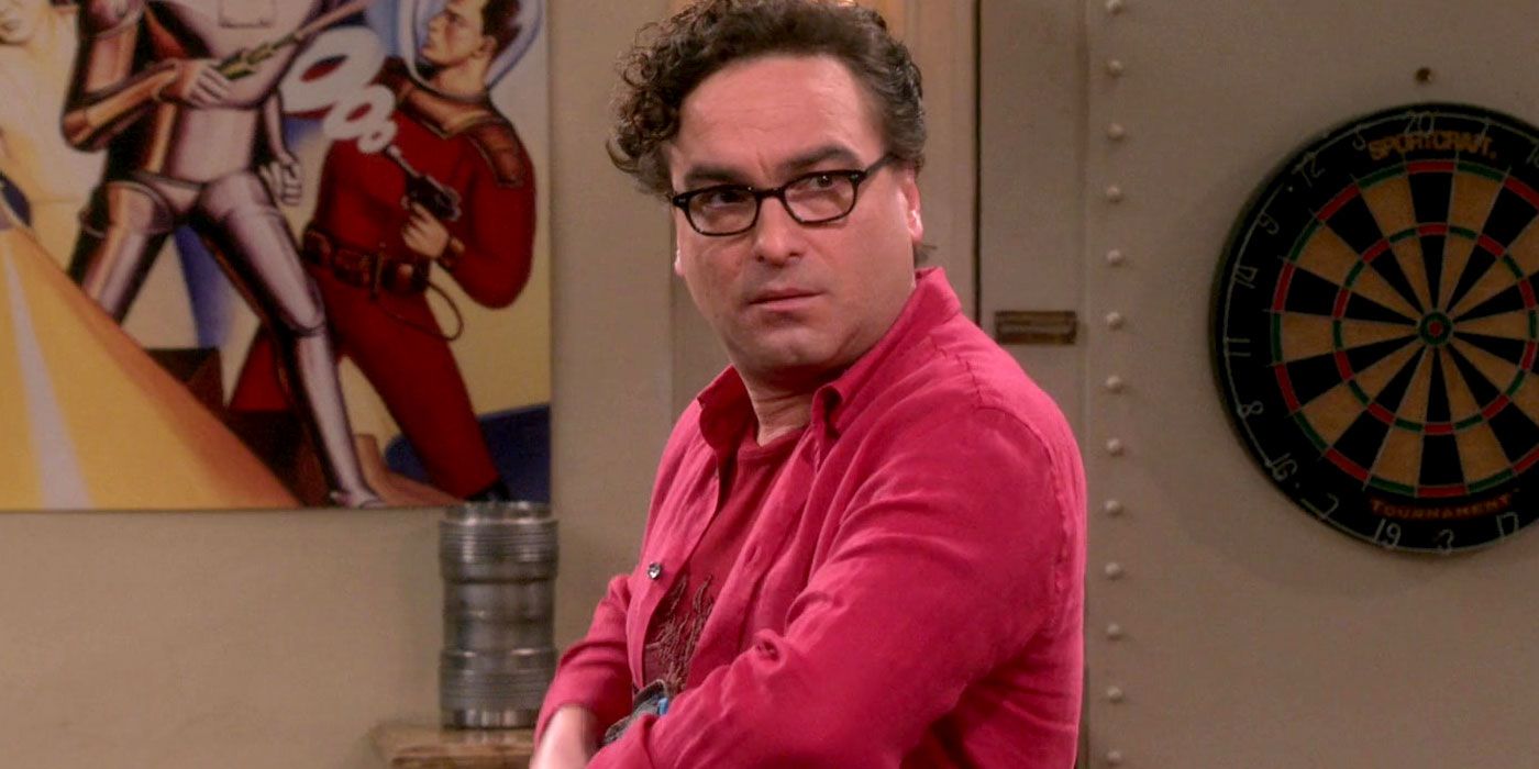 Leonard from The Big Bang Theory wearing a pink shirt, looking over at someone.