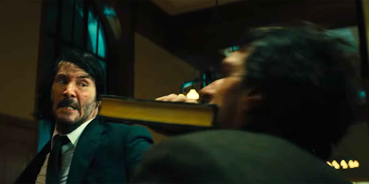 Keanu Reeves as the titular character, hitting a man with a book in John Wick 3