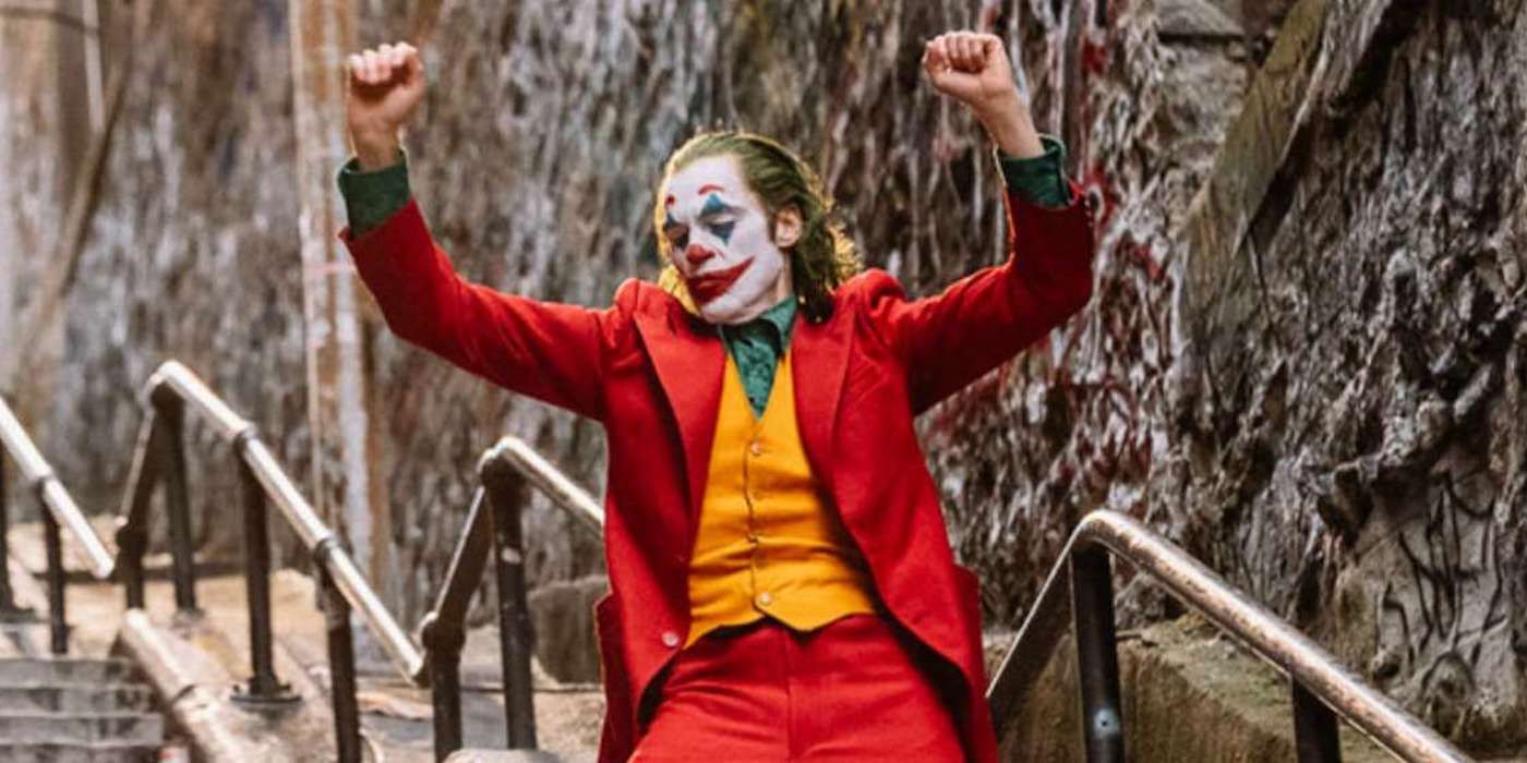 Joaquin Phoenix's Joker wears his clown costume while dancing on some steps