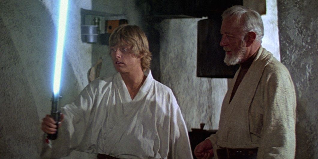Luke Skywalker holding a lightsaber with Obi-Wan Kenobi in Star Wars Episode IV A New Hope