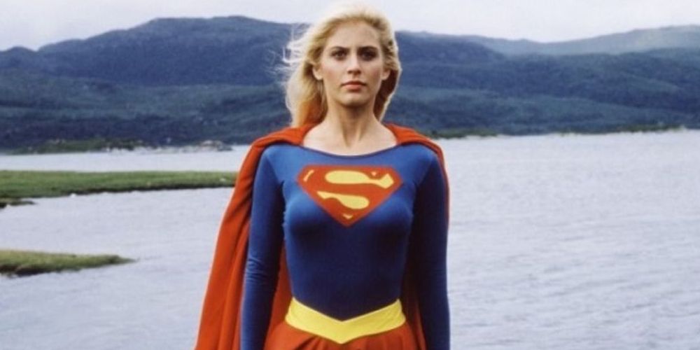 Mid-shot of Supergirl standing and looking at the camera with a lake behind her