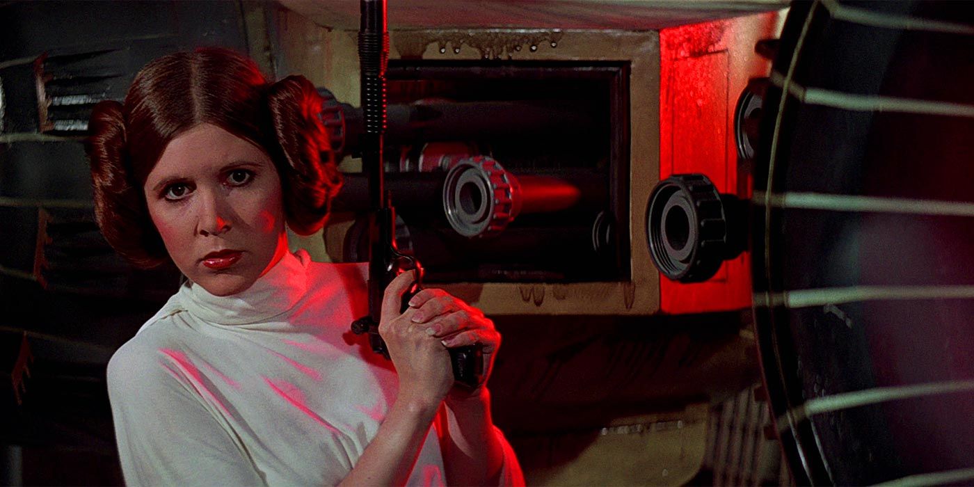 Princess Leia (Carrie Fisher) holding a blaster upright as she sneaks.
