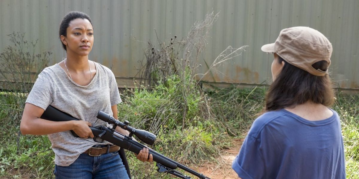 Sasha (Sonequa Martin-Green), holding her sniper rifle, talks to Rosita (Christian Serratos) in "The Other Side" in The Walking Dead
