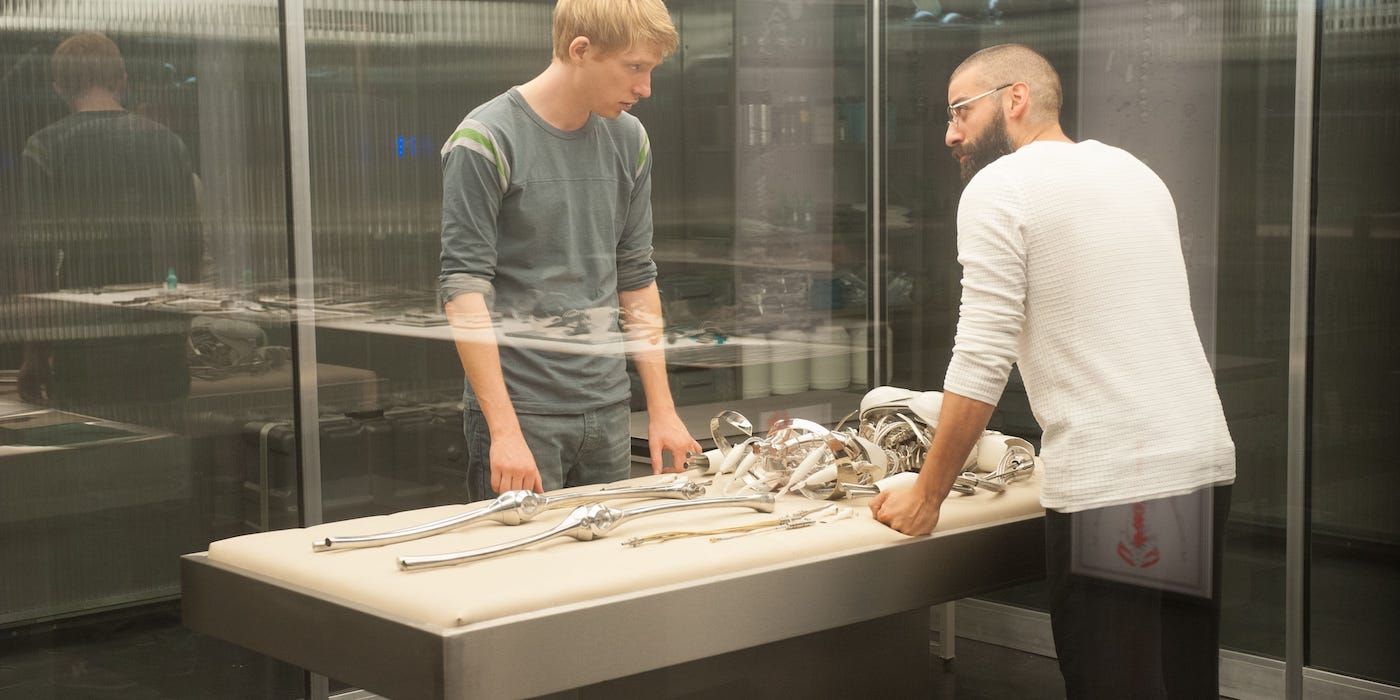 Domhnall Gleeson and Oscar Isaac stand over the insides of an android in Ex Machina.