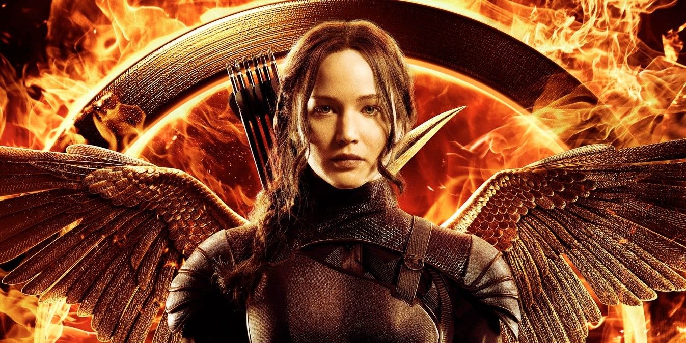 Katniss sporting mockingjay wings with a quiver of arrows on her back in front of a ring of fire in The Hunger Games.