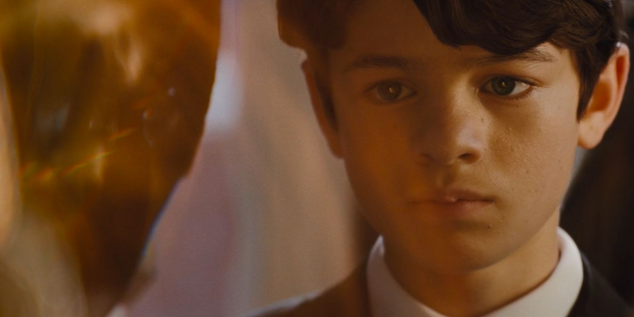 Artemis fowl looking at the Aculos, his face bathed in its golden light.