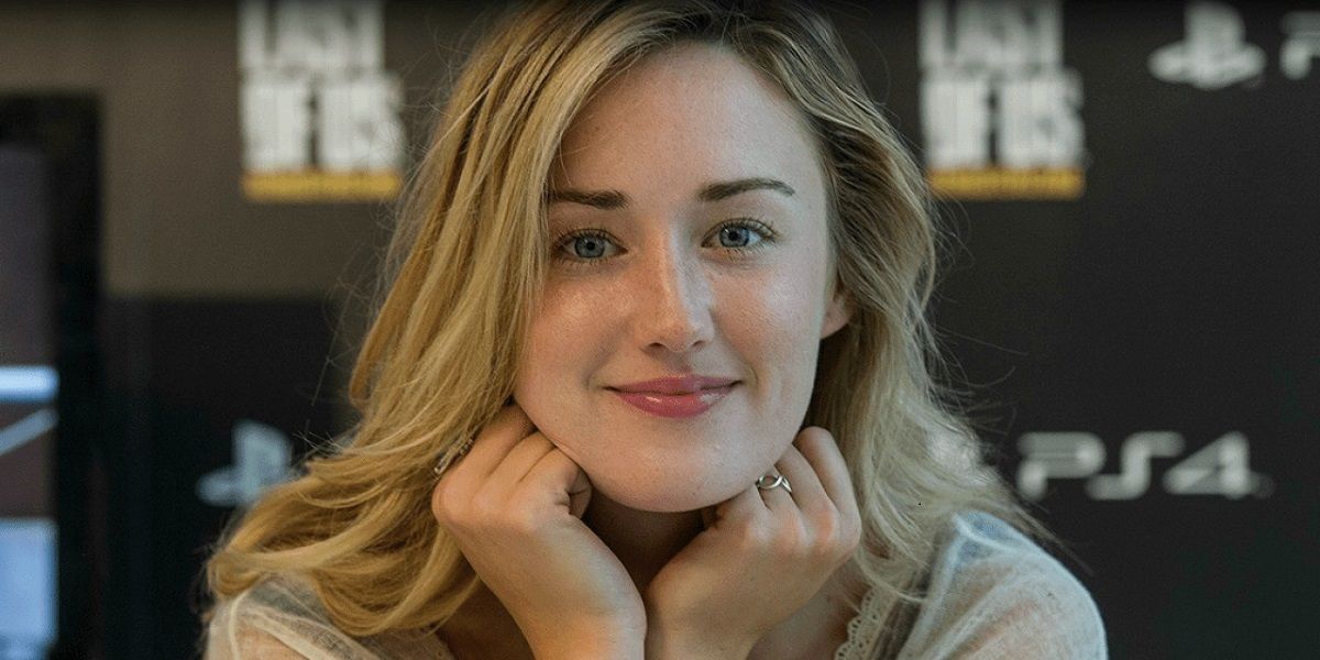 Ashley Johnson smiling with her hands under her chin.