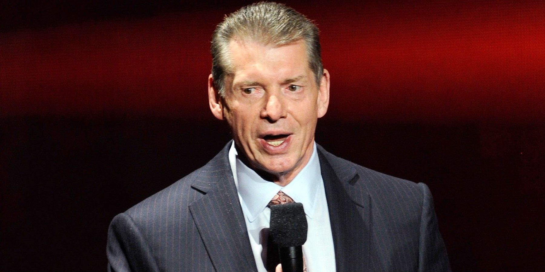 Vince McMahon speaking in front of a microphone.