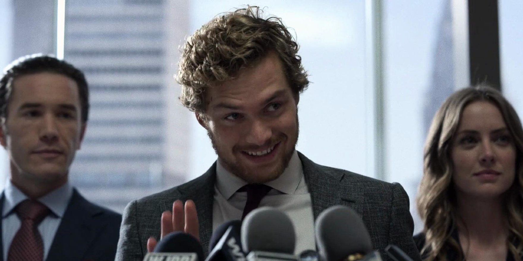 Danny Rand (Finn Jones) fala ao público com Ward e Joy Meachum ao fundo em Iron Fist da Netflix