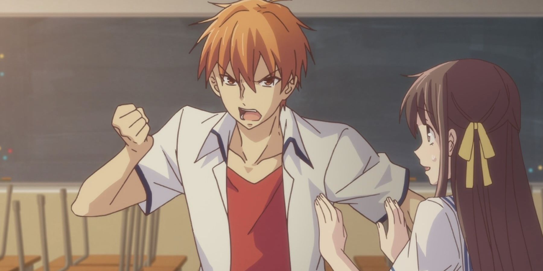 Kyo Sohma looking angry in Fruits Basket and shaking his fist as Tohru tries to calm him. 