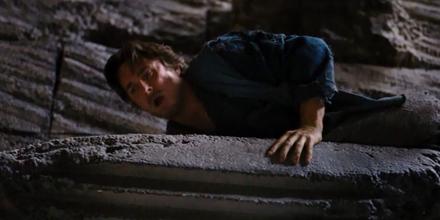 Bruce Wayne looks down over a ledge while escaping The Pit in The Dark Knight Rises