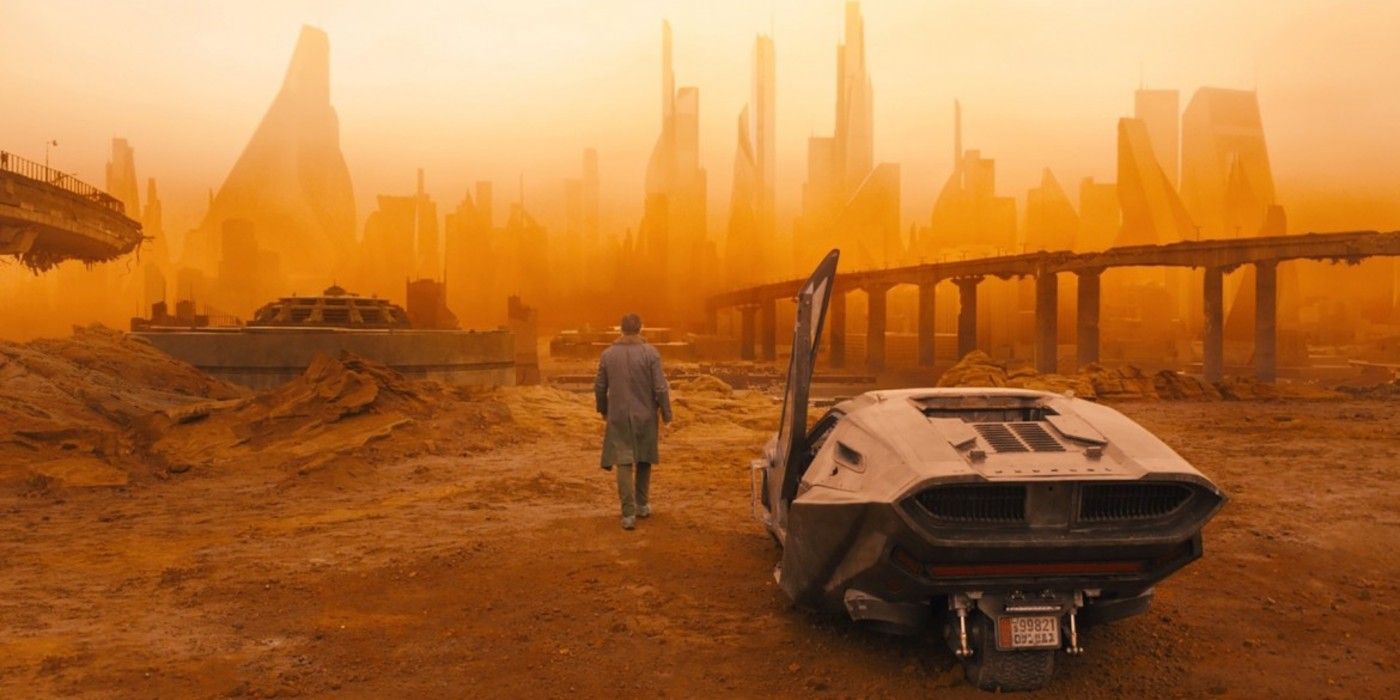 K (Ryan Gosling) walks through a barren wasteland, with skyscrapers off in the distance