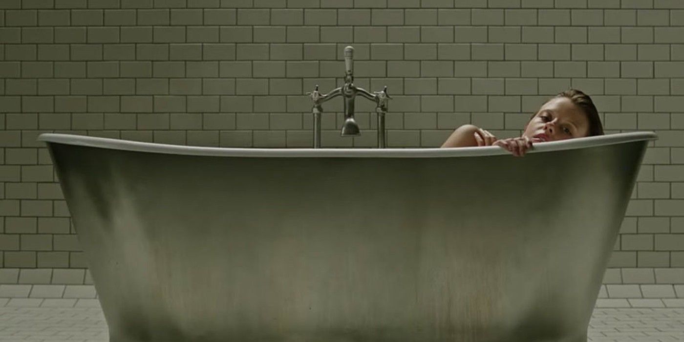 Hannah (Mia Goth) coloca a mão na borda de uma banheira durante A Cure For Wellness