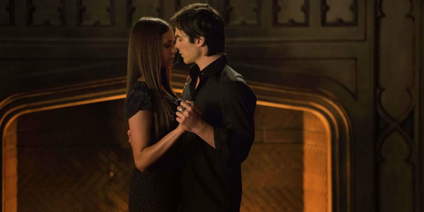 Damon and Elena dancing close together by a fireplace in The Vampire Diaries.