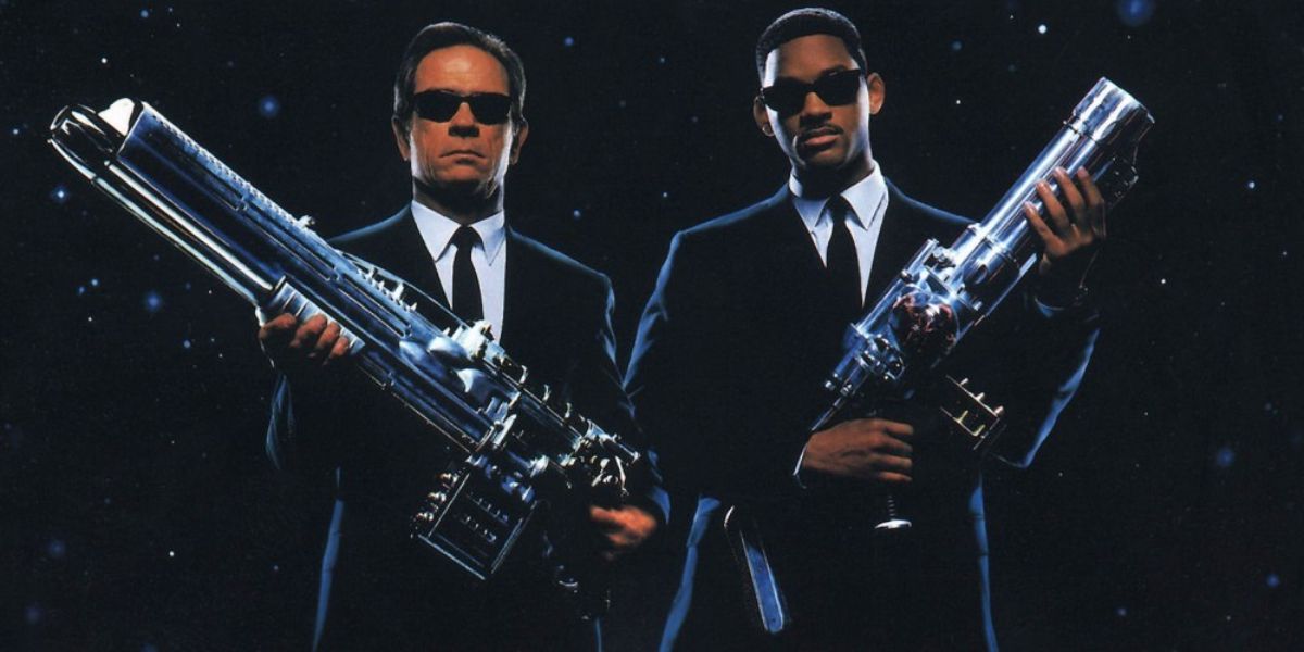 Agent J and Agent K brandish their guns in front of a space background.