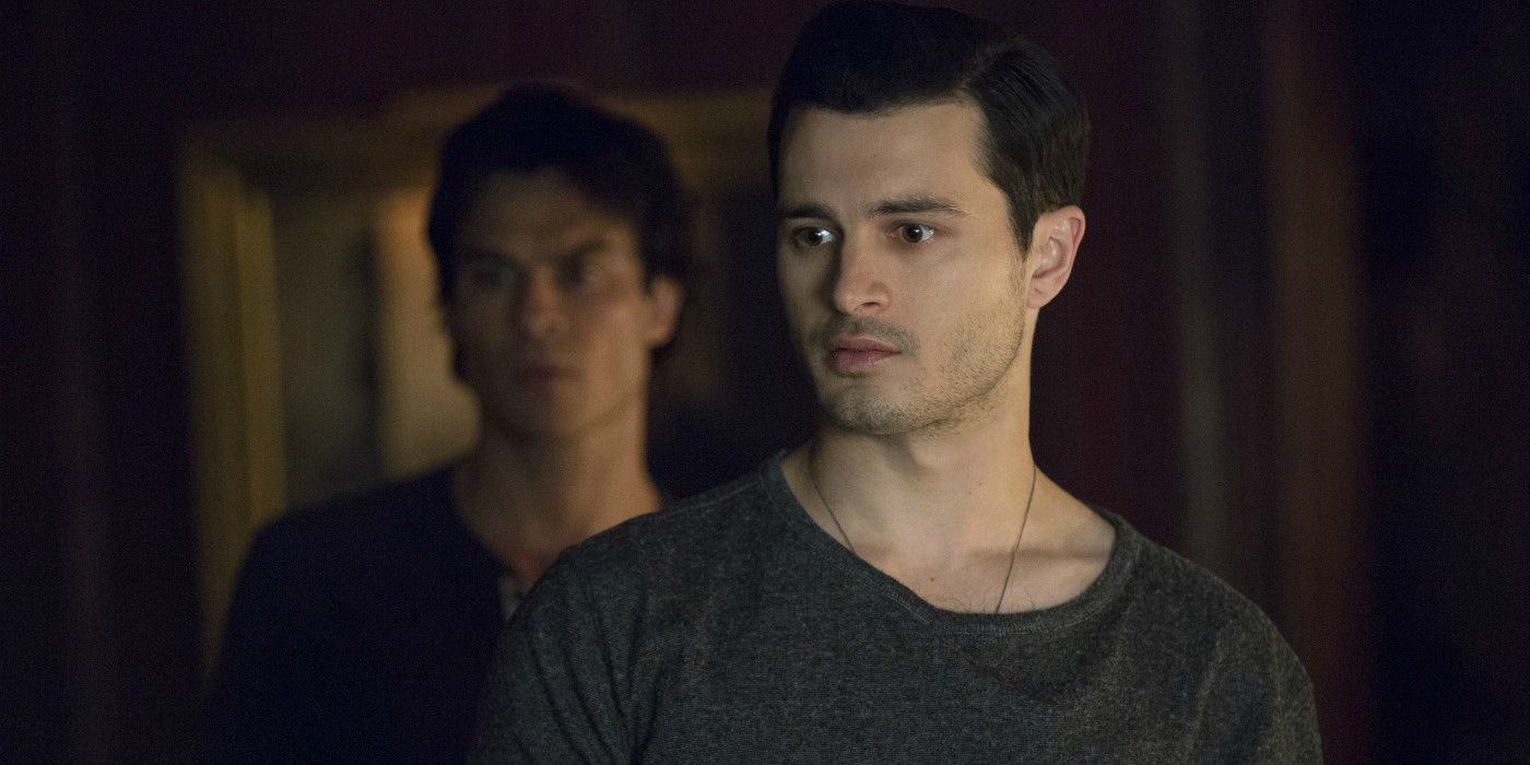 Enzo (played by Michael Malarkey) stands in front of Damon (played by Ian Somerhalder) in The Vampire Diaries