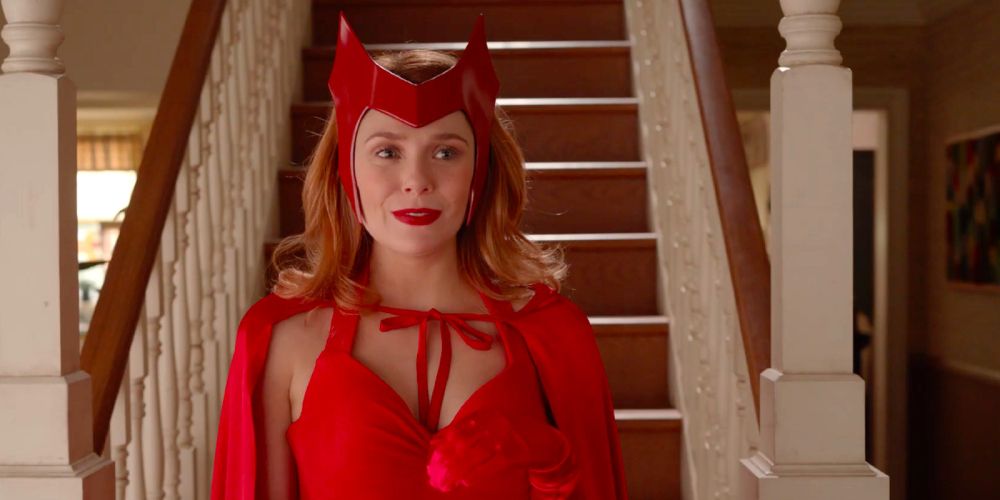 Scarlet Witch stands in front of staris in a suburban hoem wearing her original comic book costume