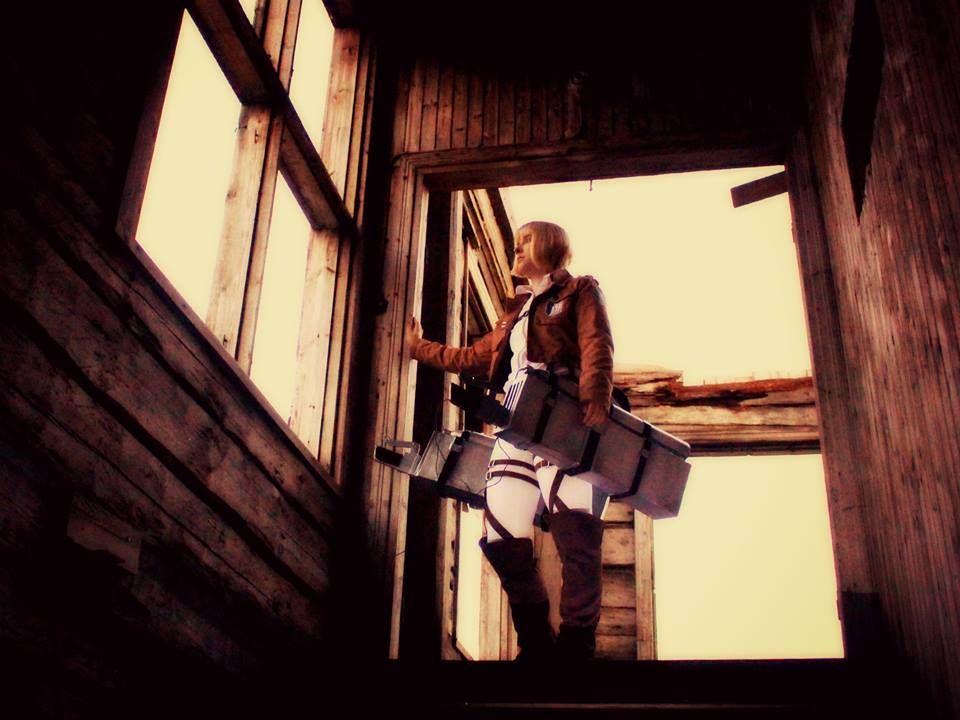 Armin cosplay looking out the window and brown light of sunset has is illuminating him.