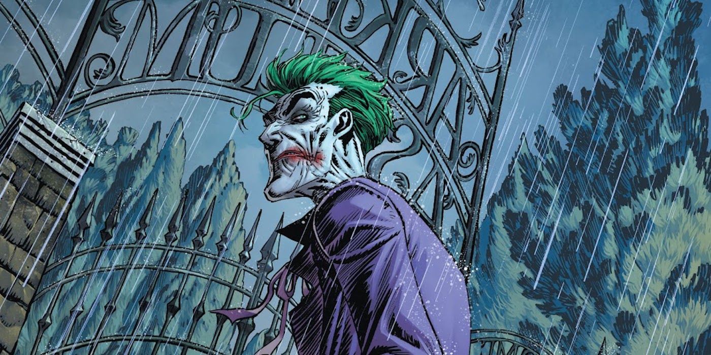 The Joker standing at Arkham Asylum's gates while it rains in DC Comics