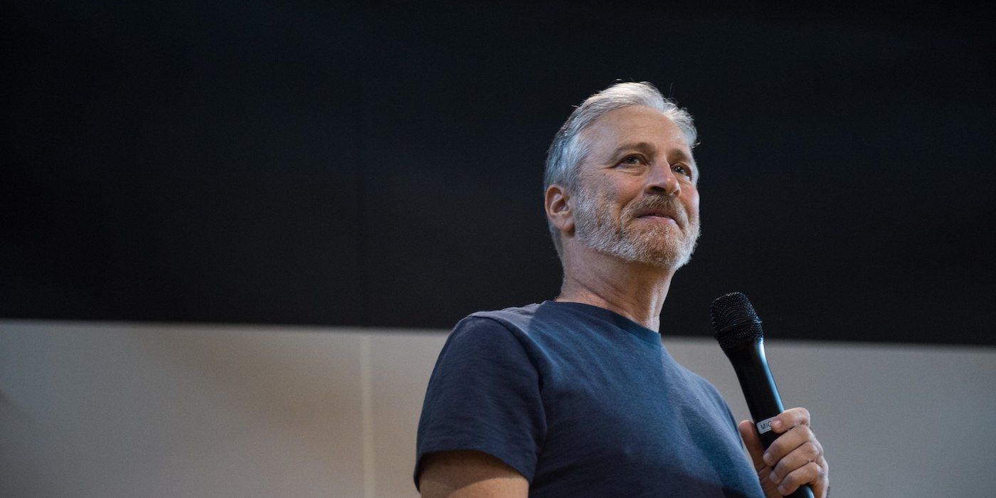 Image of Jon Stewart smiling and holding microphone