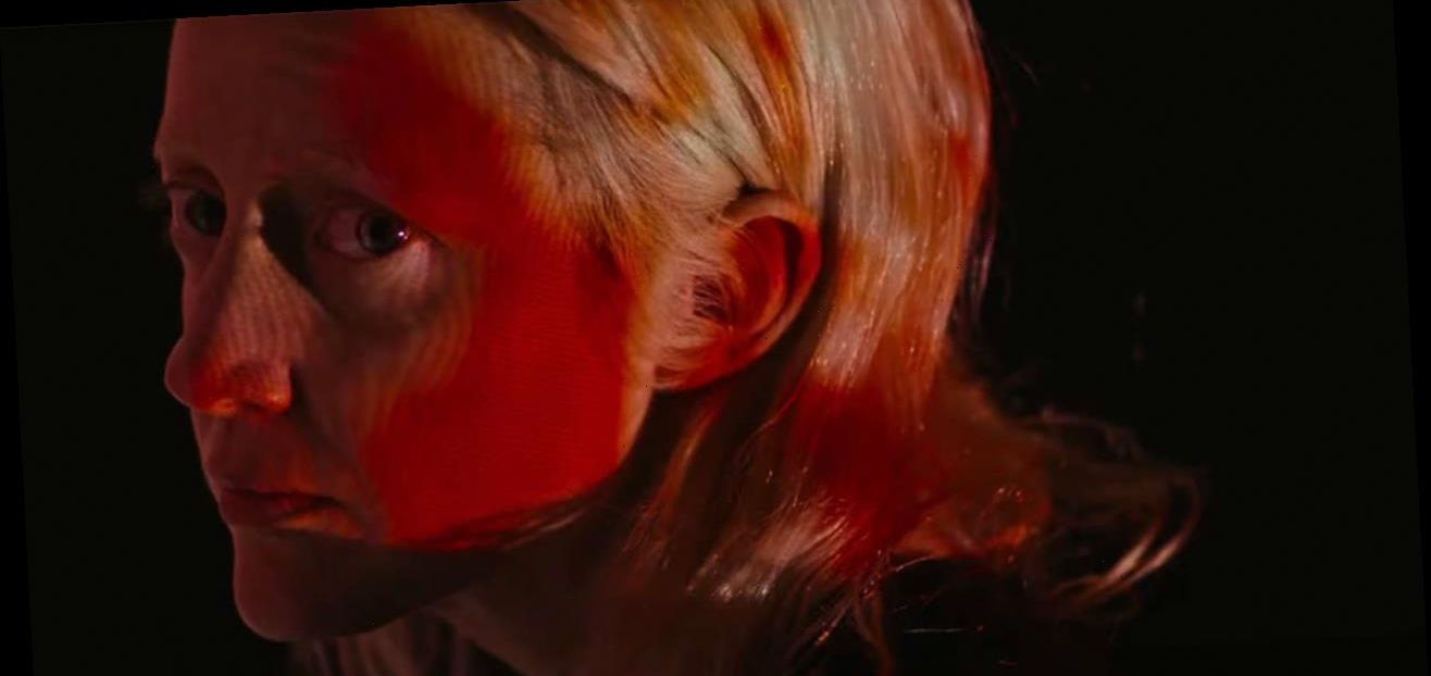Andrea Riseborough as Tasya Vos covered in red looks at the camera in Possessor