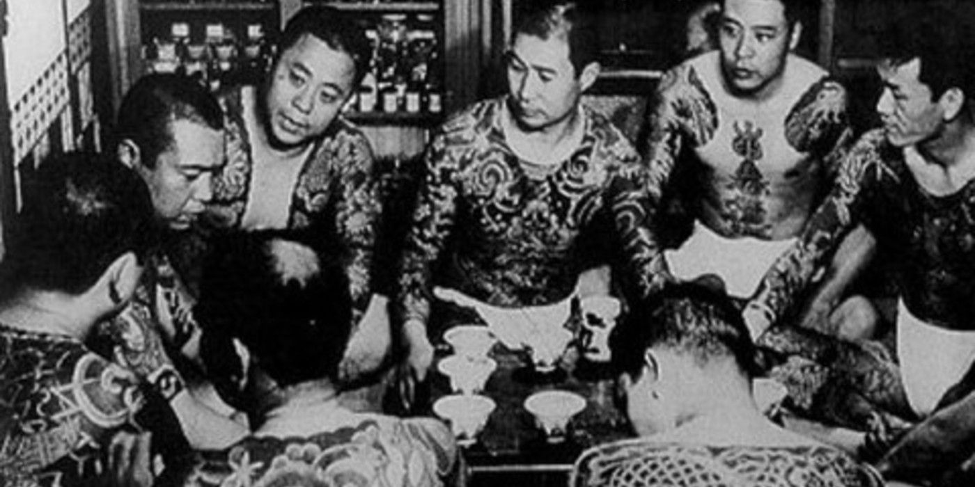 Black and white image of the yakuza sat around in a circle