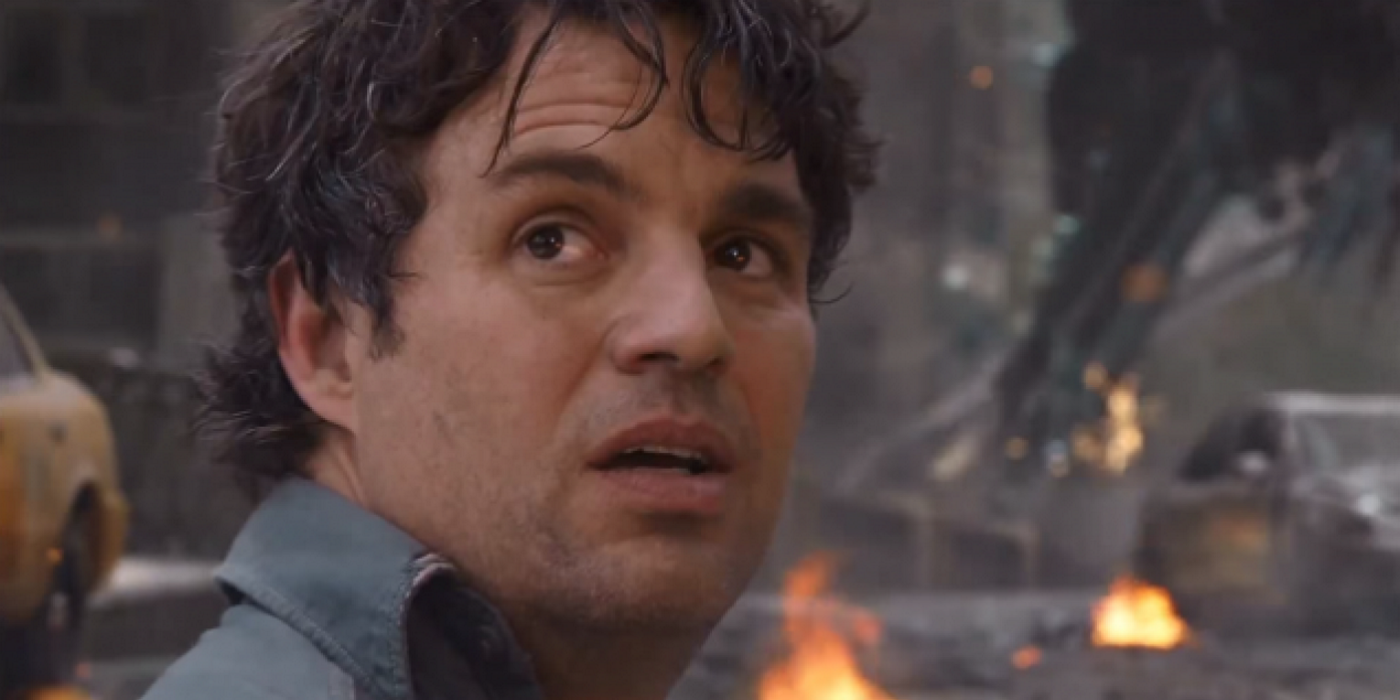 a close-up of bruce banner with a fire in the distance
