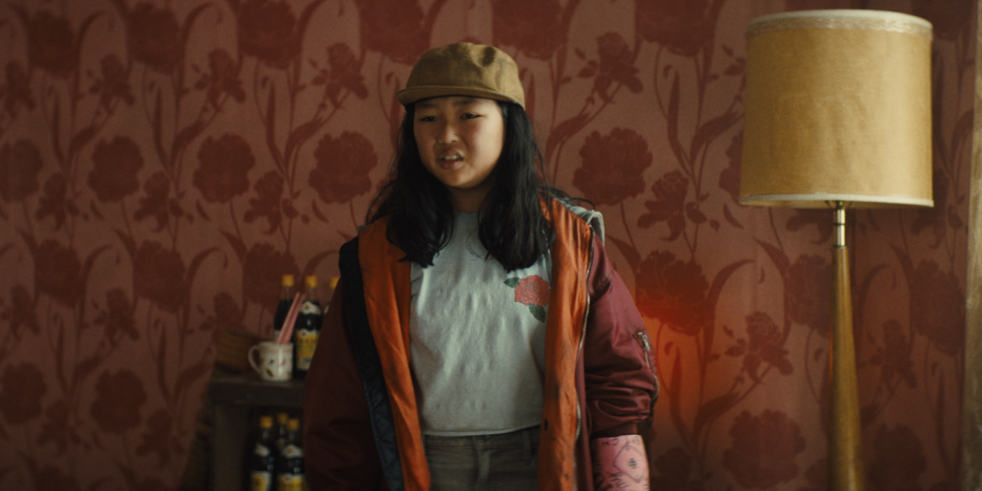 a young girl looking confused with a red wallpaper behind her