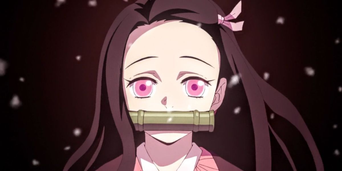 A close-up of Nezuko wearing her bamboo muzzle as snow falls around her