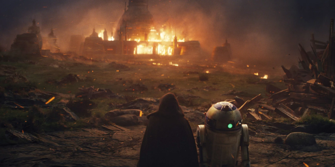 Luke Skywalker and R2-D2 outside the burning Jedi Temple in Star Wars.