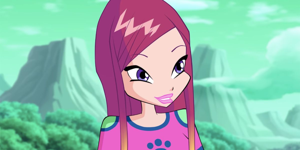 Roxy from Winx Club smiling with green trees and mountains in the background.