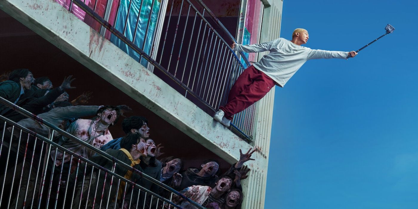 A man hanging from a balcony as zombies reach for him in Hashtag Alive.