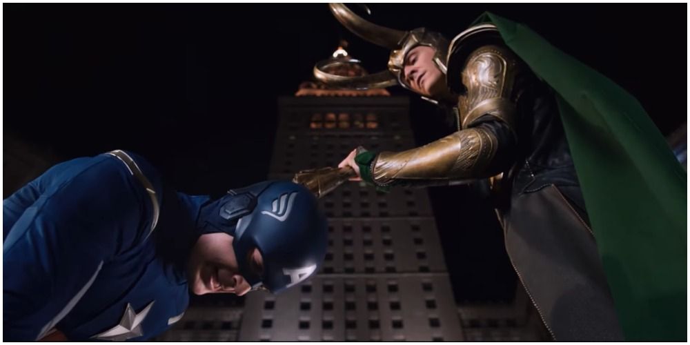 Loki holding his staff to Cap's head